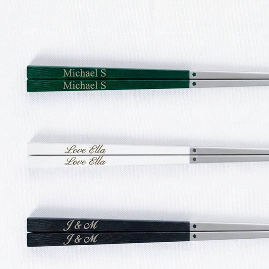 Custom engraved 316 stainless steel chopsticks with wood-grain handles in green, white, and black, showing personalized name engravings "Michael S," "Love Ella," and "J & M."