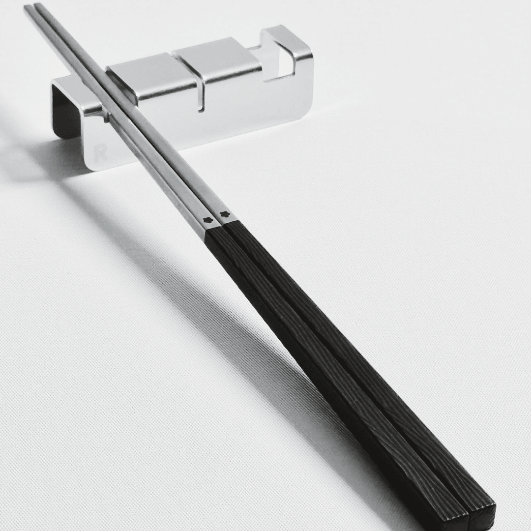 316 stainless steel silver chopsticks with black resin handle with 304 stainless steel utensil rest set on a light gray background