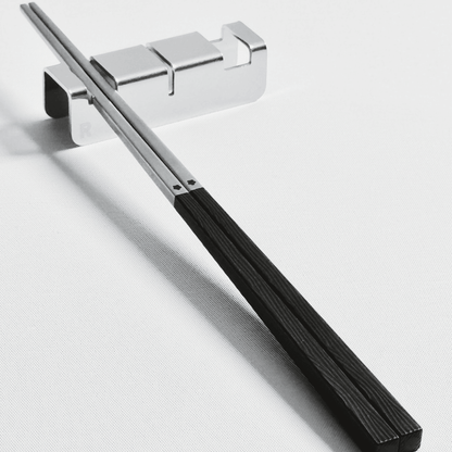 316 stainless steel silver chopsticks with black resin handle with 304 stainless steel utensil rest set on a light gray background