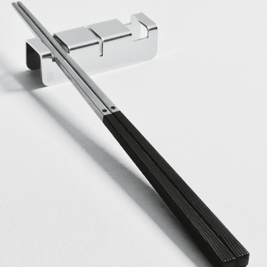 316 stainless steel silver chopsticks with black resin handle with 304 stainless steel utensil rest set on a light gray background