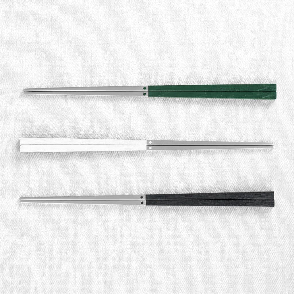 Three 316 stainless steel chopsticks with three different colored handles green, white and black on a white background