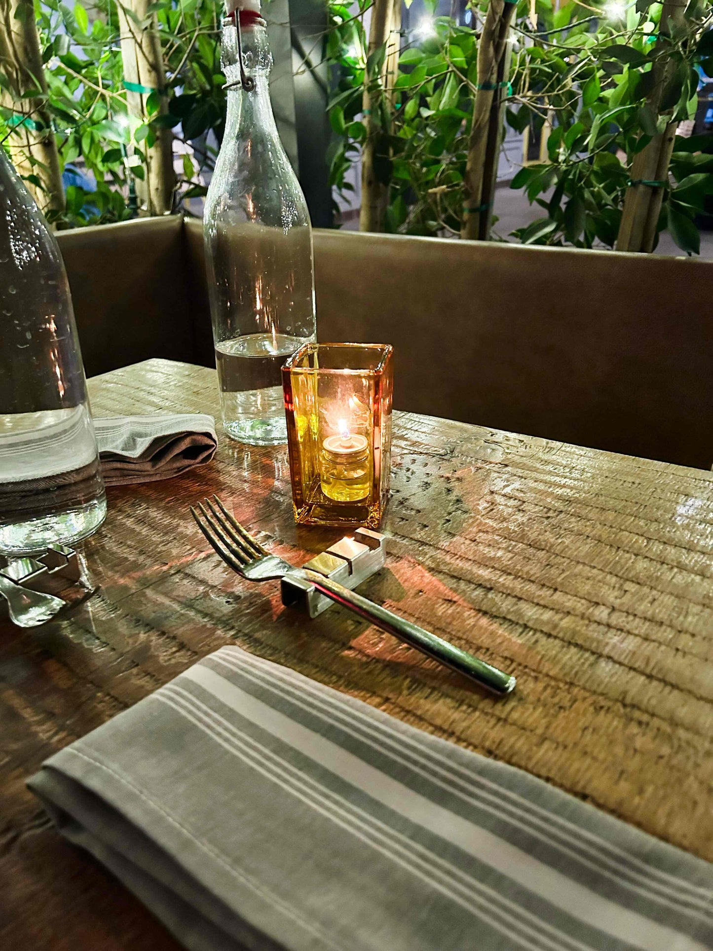 Two polished silver stainless steel chopstick rests displayed on a white linen surface, next to a folded kraft-paper pillow gift box tied with twine and embossed with the "RADIKO" logo.