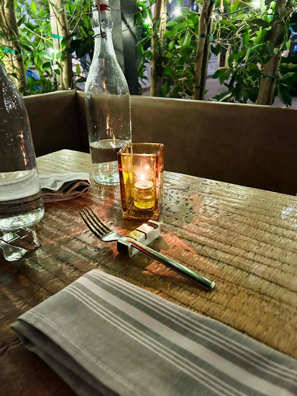 Two polished silver stainless steel chopstick rests displayed on a white linen surface, next to a folded kraft-paper pillow gift box tied with twine and embossed with the "RADIKO" logo.